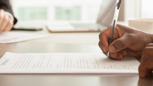 Horizontal closeup image businessman sitting at desk signing contract